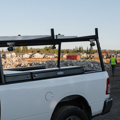 White truck with three boxes in it's bed and a construction site in the background